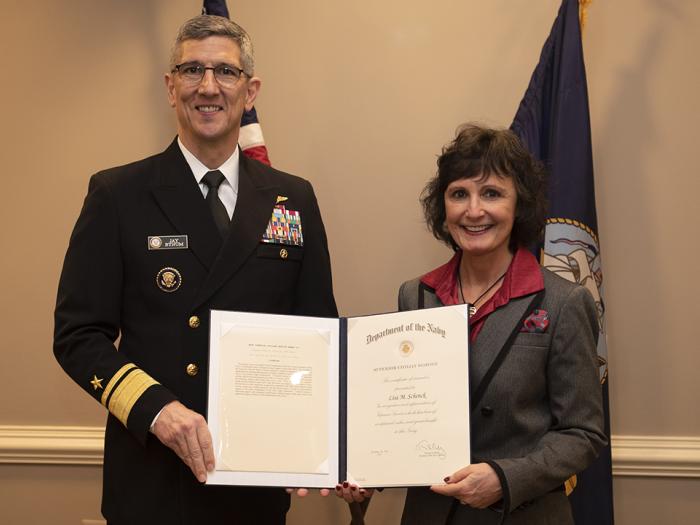 Associate Dean Lisa M. Schenck receives an award from Rear Admiral (Upper Half) Jay Bynum. 