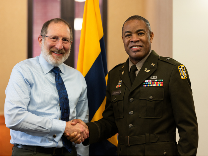 Two men shaking hands and looking at the camera smiling