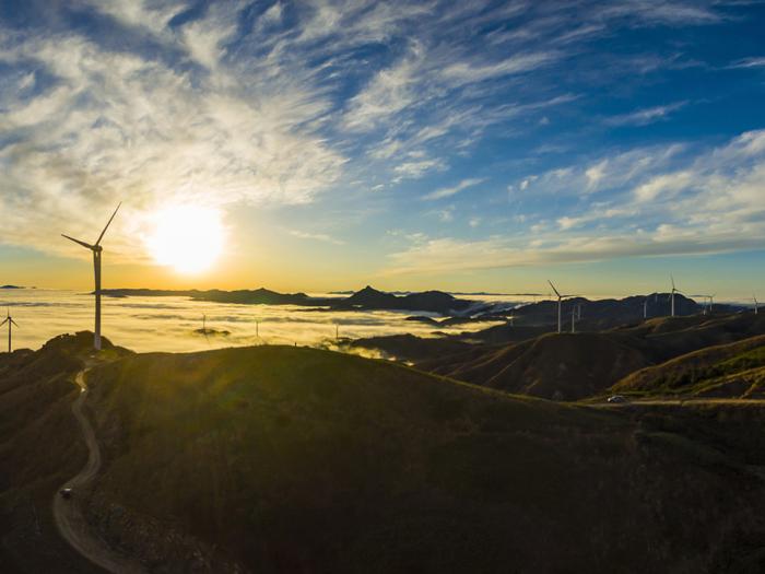 Image of a sunrise overlooking a valley of wind turbines