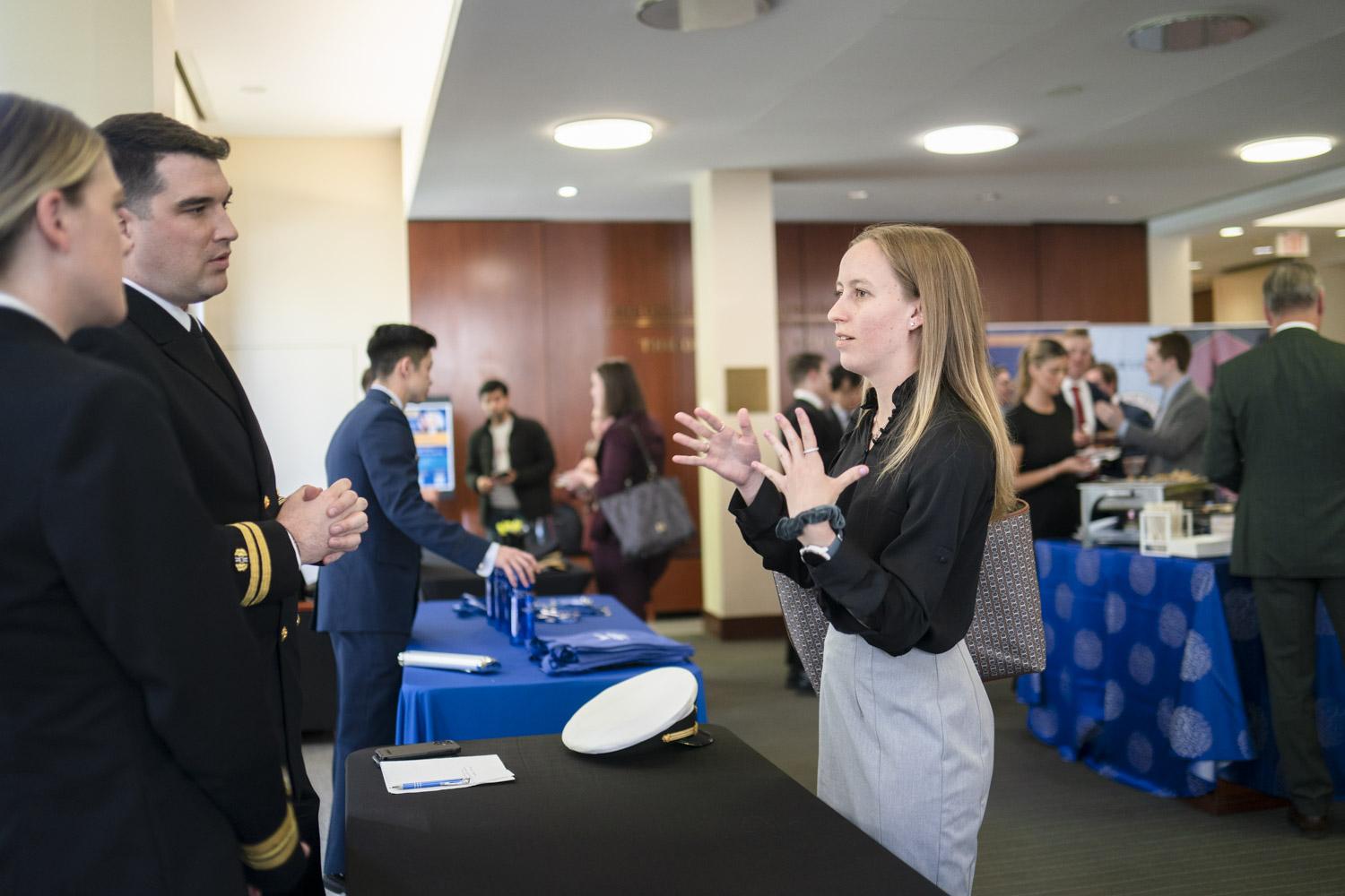 A student talking to military members at a reception