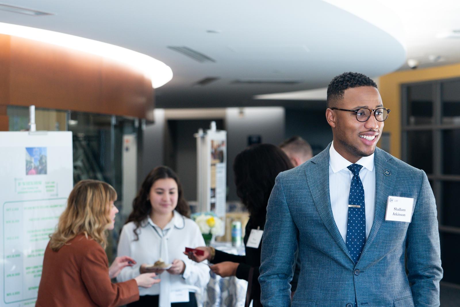 people in the background and Shallum Atkinson in the forefront smiling at a person off camera