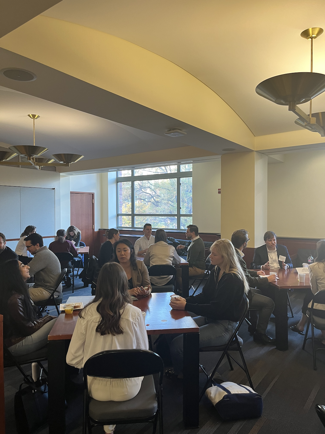 Alumni and students sitting at table and talking while eating pastries