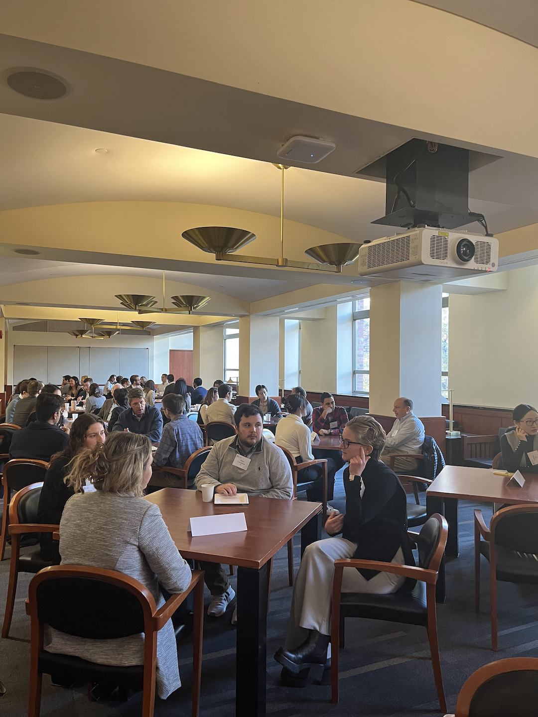 Alumni and students sitting at table and talking while eating pastries