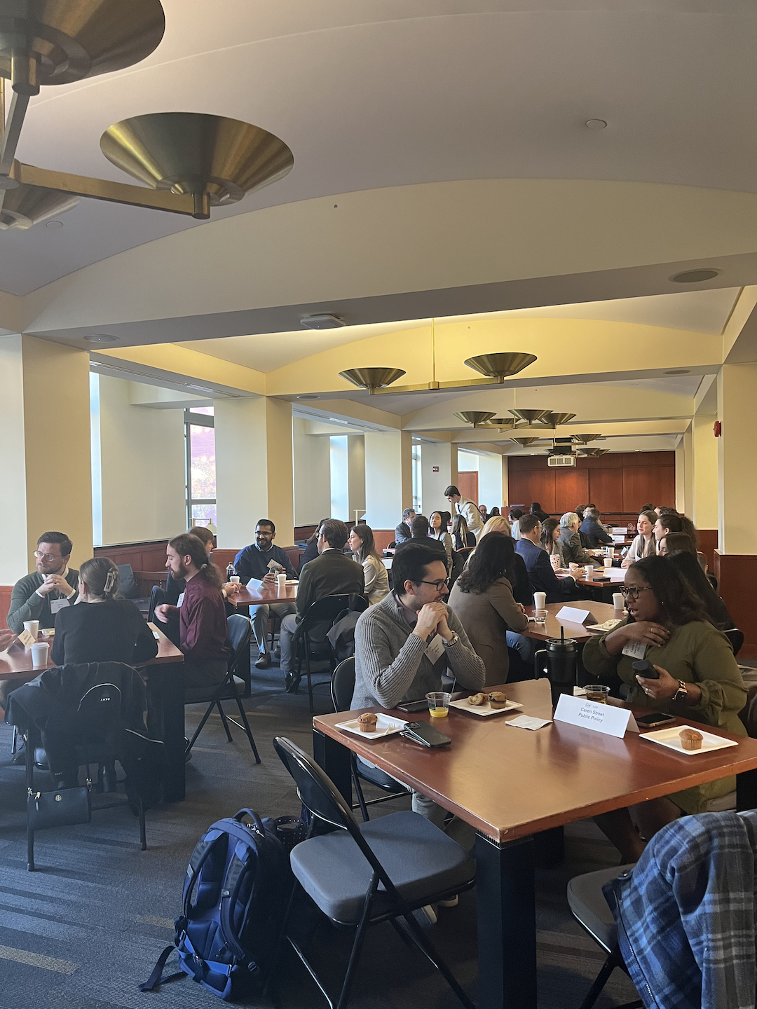 Alumni and students sitting at table and talking while eating pastries