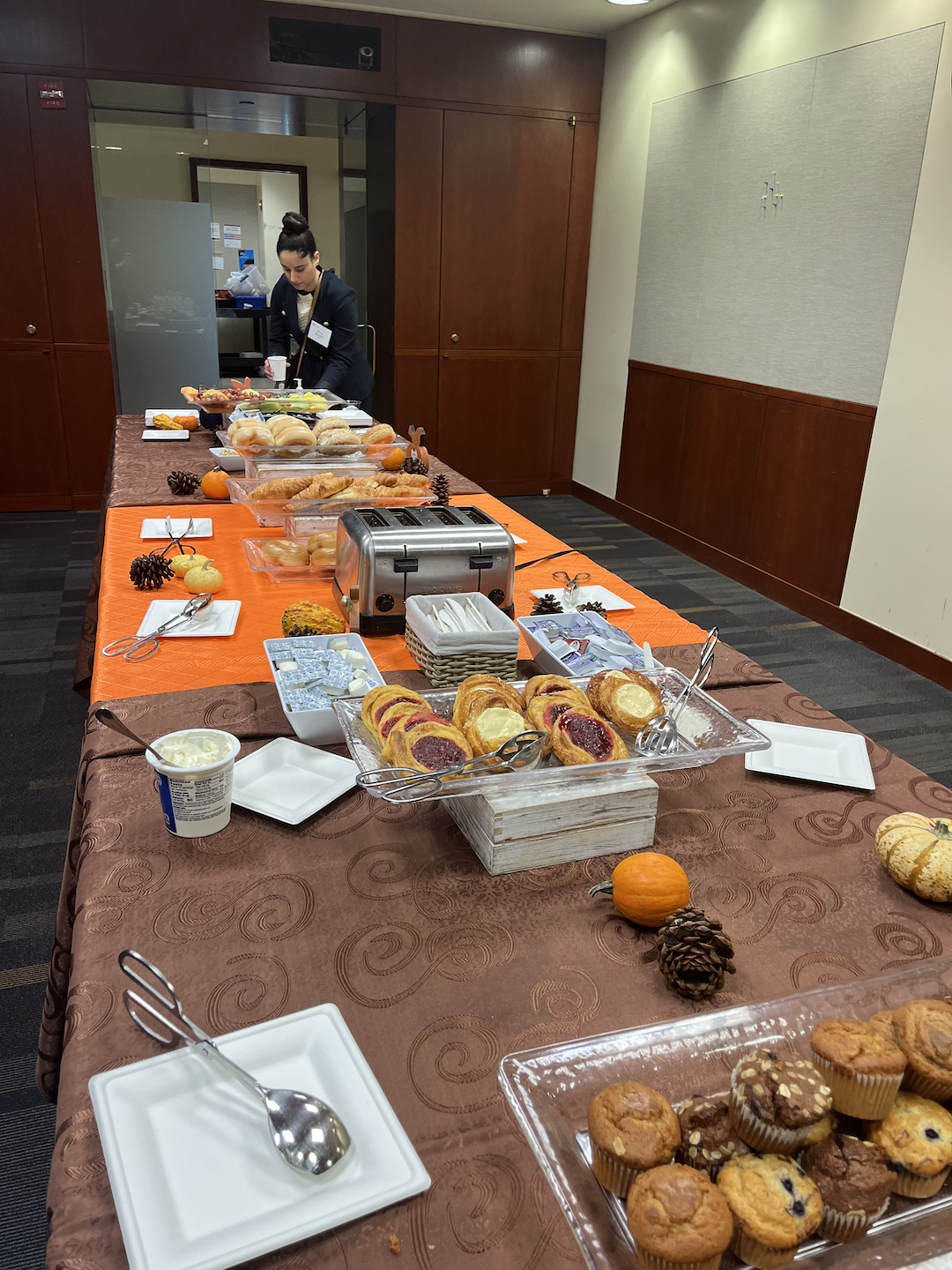 A table of breakfast pastries and a girl picking what she would like from the table