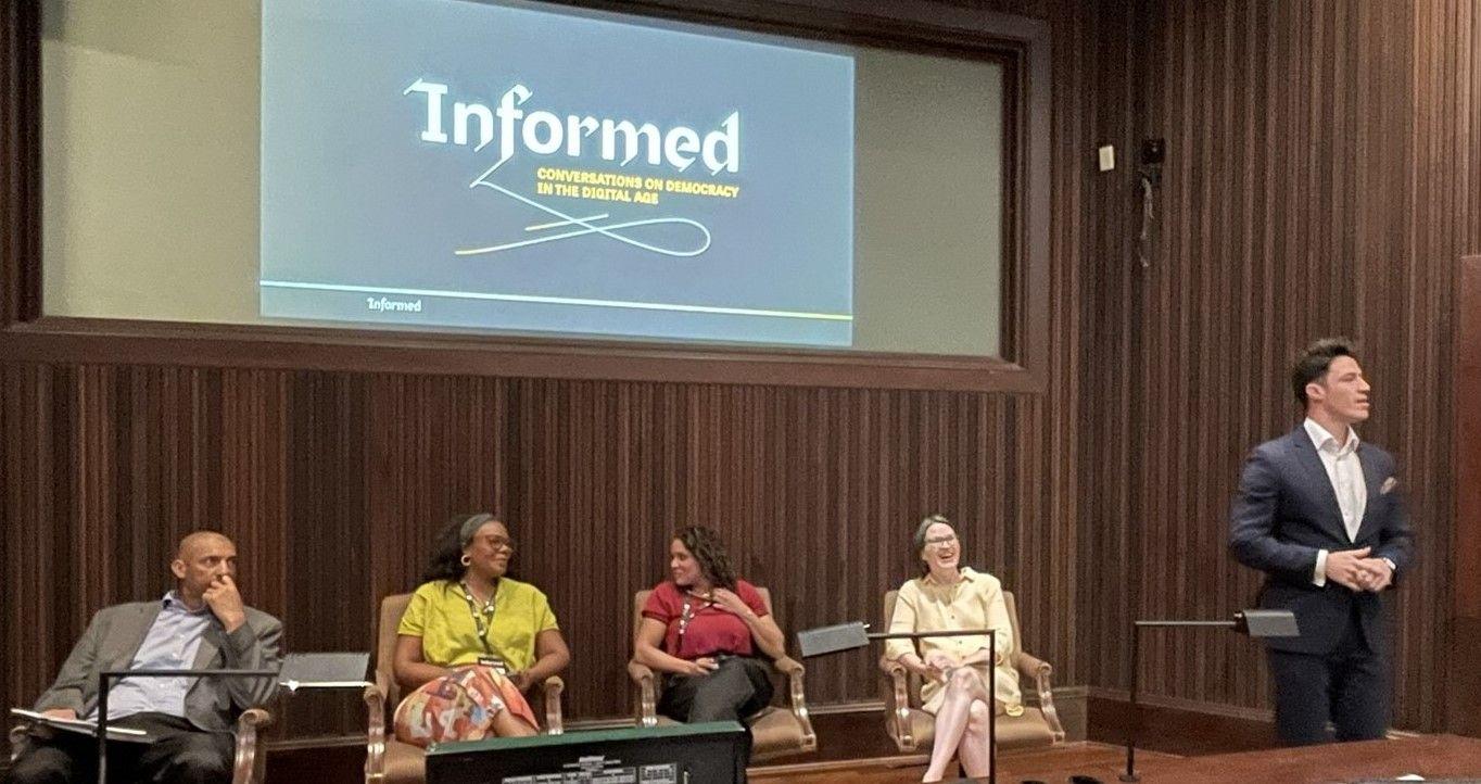 Spencer Overton and 3 colleagues sitting watching a man speak