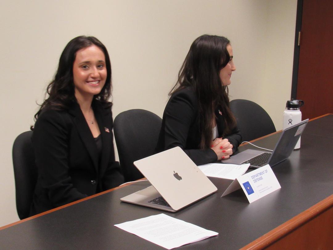 Alex Greenberg and Talia Spillerman sitting at a table with Talia smiling and Alex looking the other way