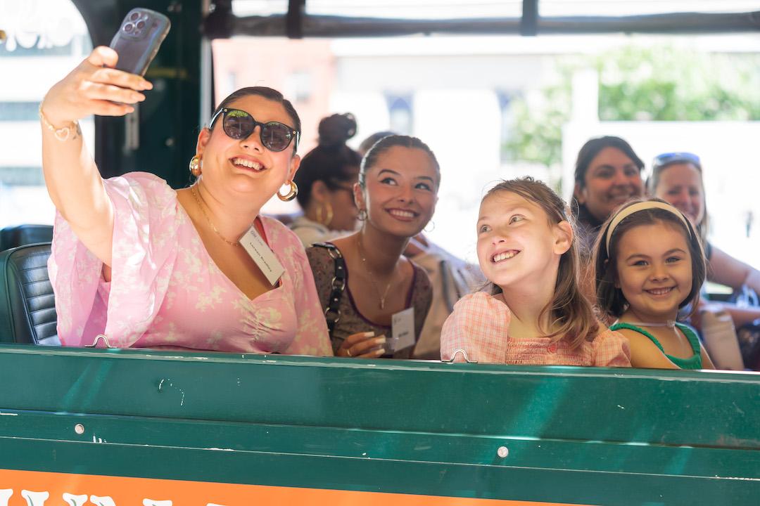 A woman taking a selfie photo with her three kids on a trolley