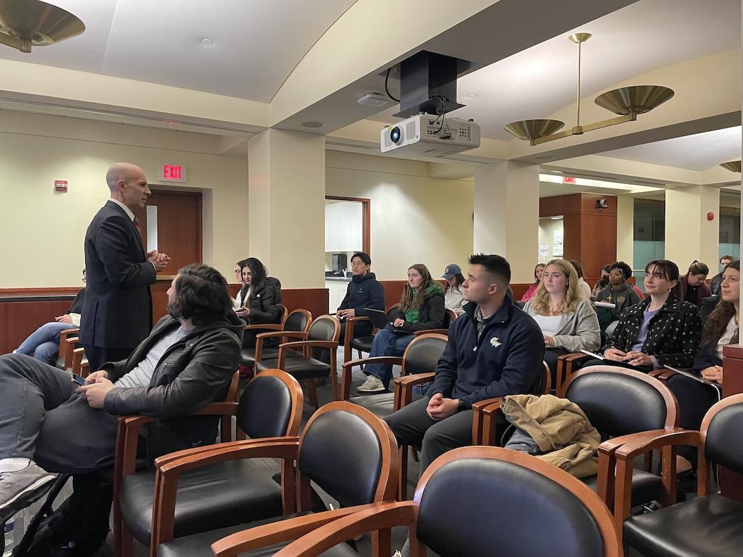 A professor speaks to an audience of students.
