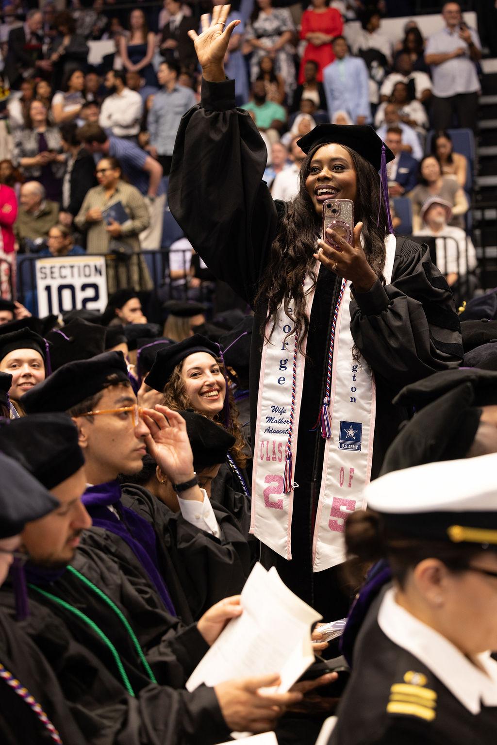 A GW Law graduate waves to the crowd during the 2025 commencement ceremony.