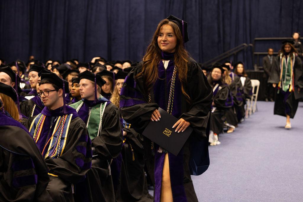 A GW Law graduate holds her diploma during the 2025 commencement ceremony