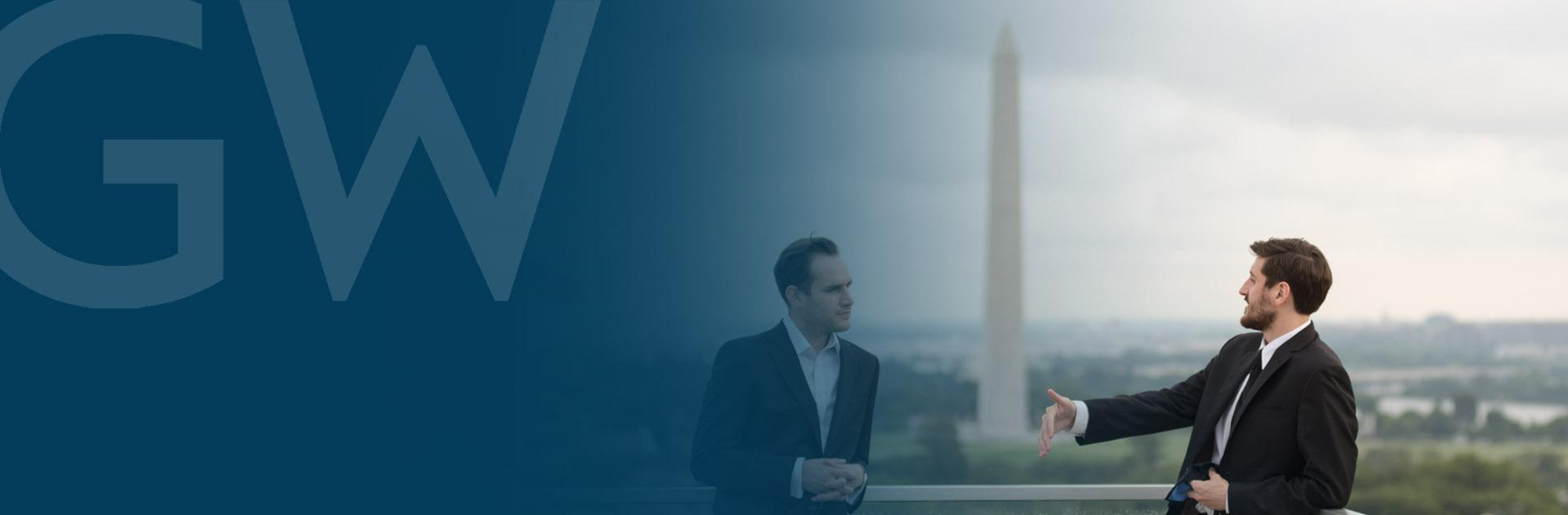 Two men standing on a roof, talking, with the Washington Monument visible in the background