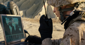 Soldier Using Laptop Computer and Radio for Communication During Military Operation in the Desert.