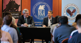 Professor Dan Richard and Eric O'Neill talking in front of a room of listeners