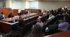Students listen to a panel of professors in the Burns Moot Court Room.
